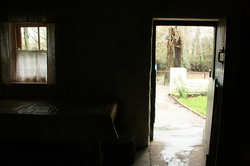 looking out from insided a dark room of a cottage through an open door into the daylight