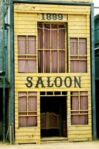 an old yellow building with 'saloon' painted over the door and '1889' painted over the second floor 